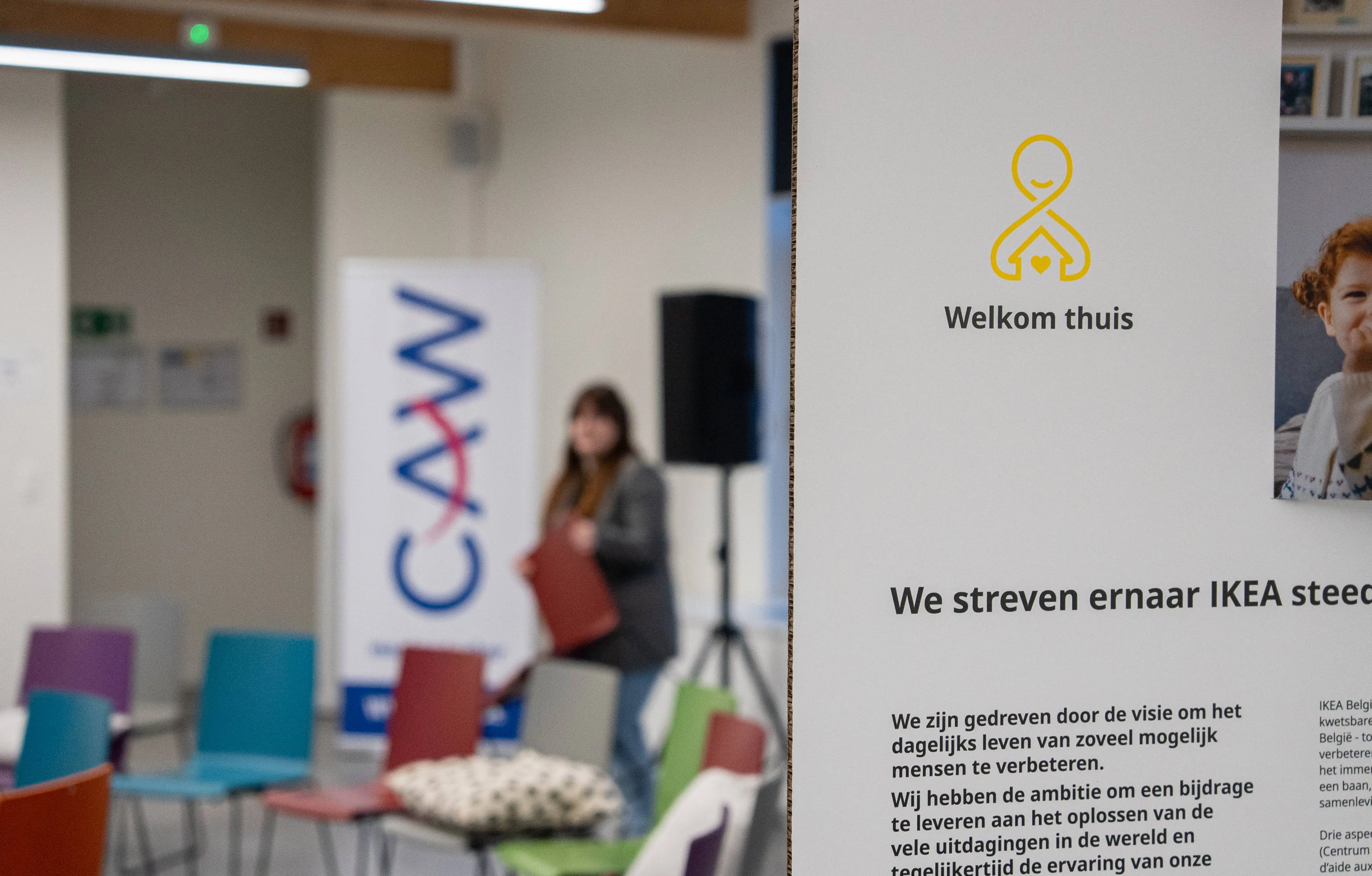Panneau de décoration indiquant le nom du projet en néerlandais “Welkom Thuis” avec en arrière fond la salle vide